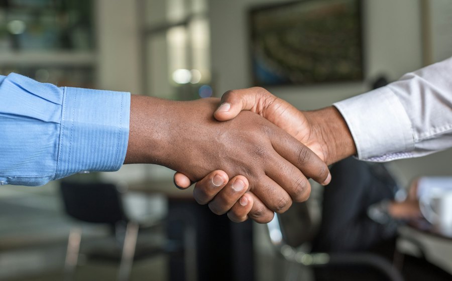 Two people shaking hands across a desk